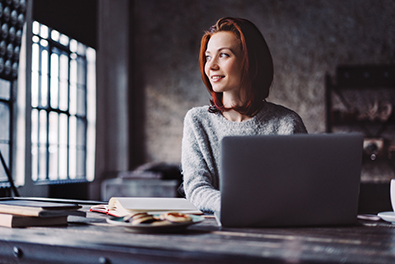 woman on laptop smiling towards window